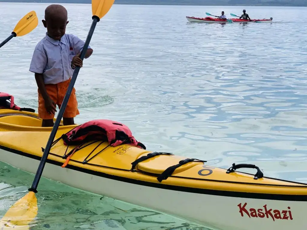 a boy standing while kayaking in Raja Ampat